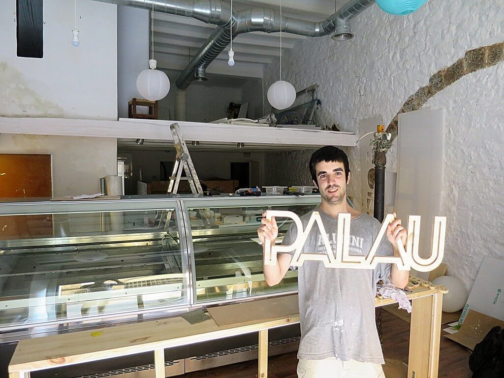 Nacho sosteniendo el cartel PALAU en el local casi terminado